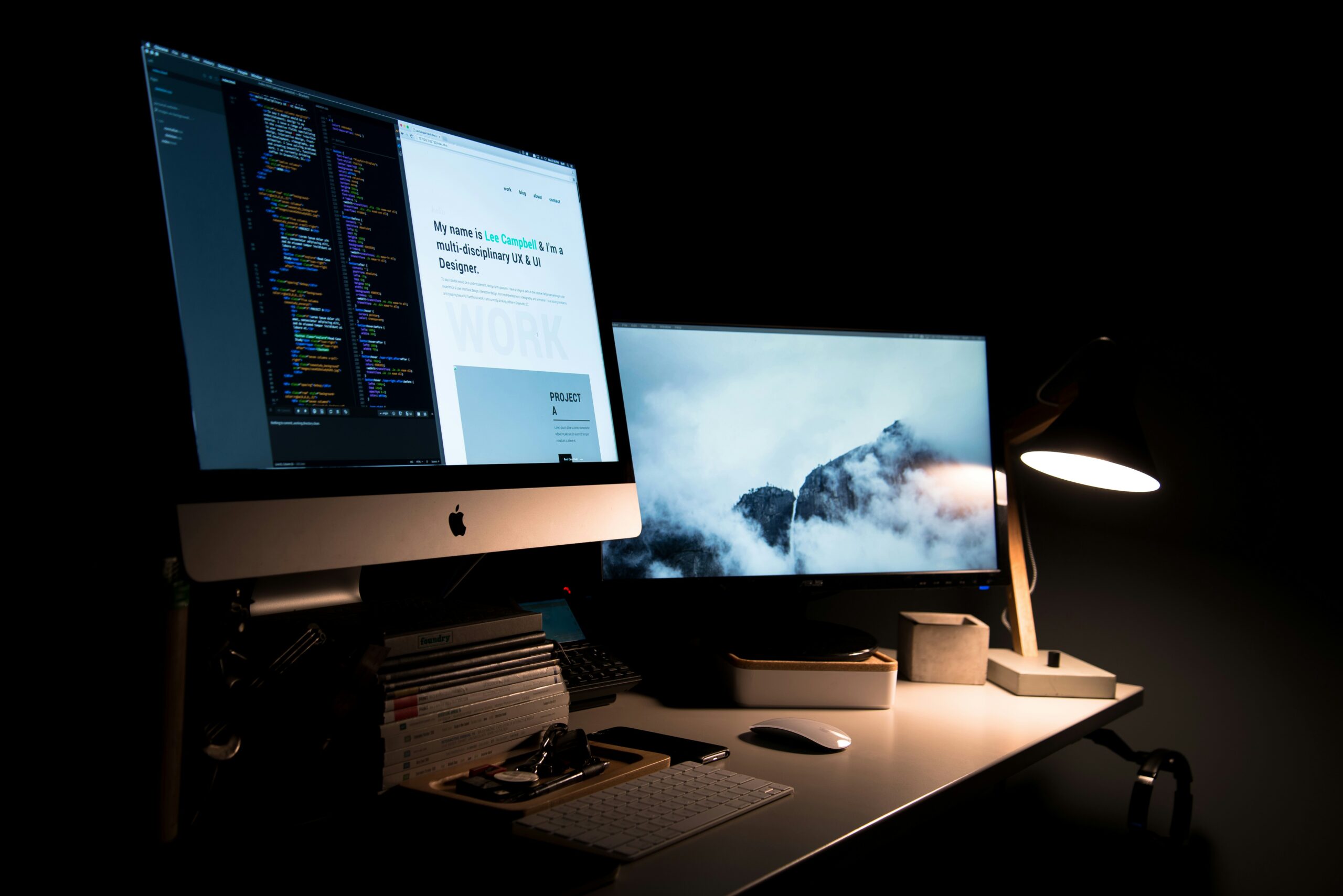 Dual monitors with website code and a design preview in a dark workspace, highlighting professional web development and modern digital marketing strategy.