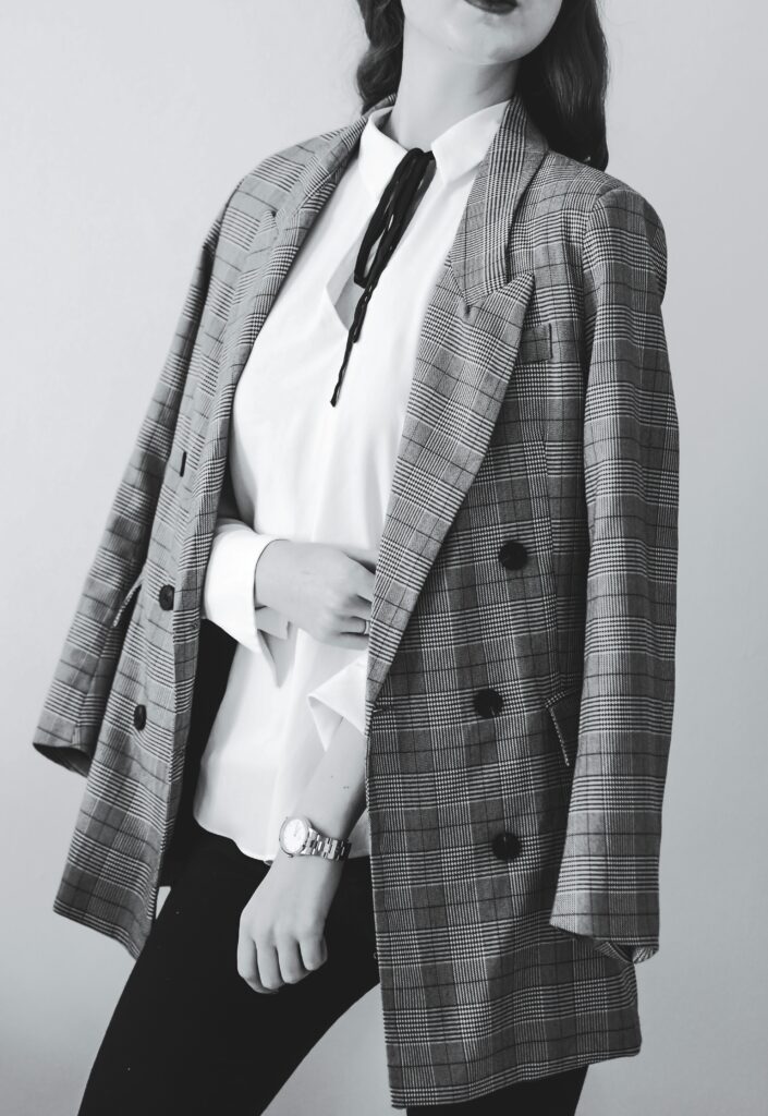 Fashionable woman wearing a stylish checked blazer and white blouse with black ribbon
